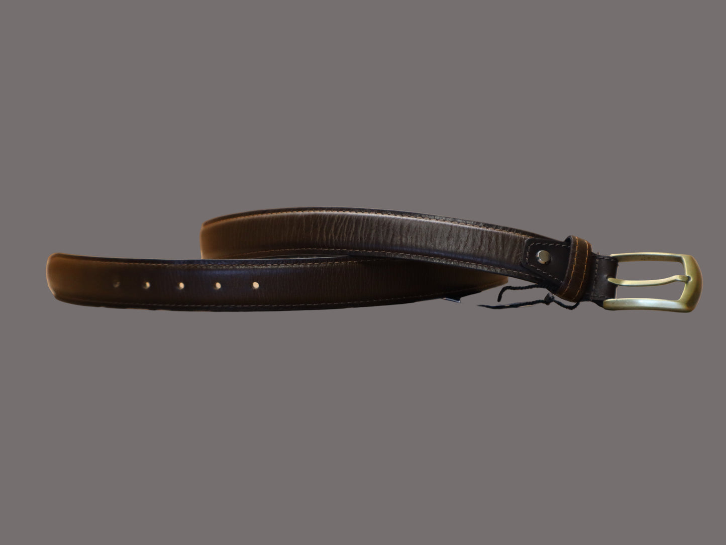 chestnut brown leather belt with a gold buckle on a beige surface