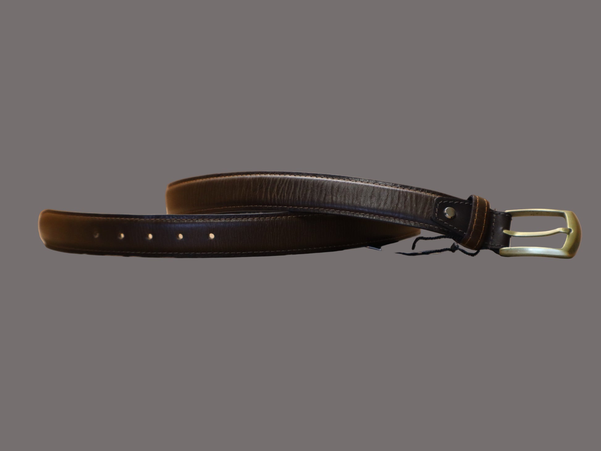chestnut brown leather belt with a gold buckle on a beige surface